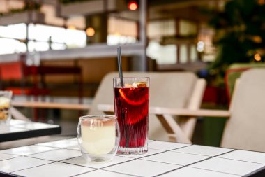 Bir yaz restoranında iki meyve kokteyli tatlısı. Tatlı çikolatalı vanilyalı tatlı ve büyük bardakta meyve suyu. Kapat..