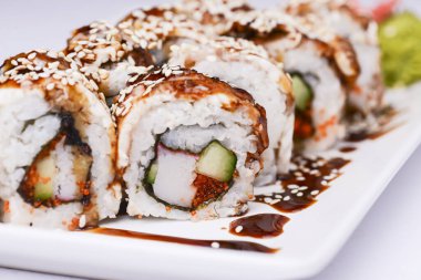 Beyaz arka planda sunulan unagi soslu yılan balığı, somon balığı ve ton balığı. Geleneksel Japon mutfağı, Asya mutfağı kavramı.