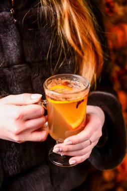 Kadın ellerinde sıcak şarap, arka planda Noel süslemeleri, yeni yıl zamanı. Soğuk hava için sıcak içecek.