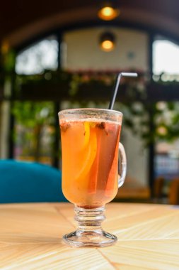 Plastik kamışlı sıcak bir bardakta, bulanık arka planda sıcak şarap. Arka planda Noel süsleri, yeni yıl zamanı. Soğuk hava için sıcak içecek.