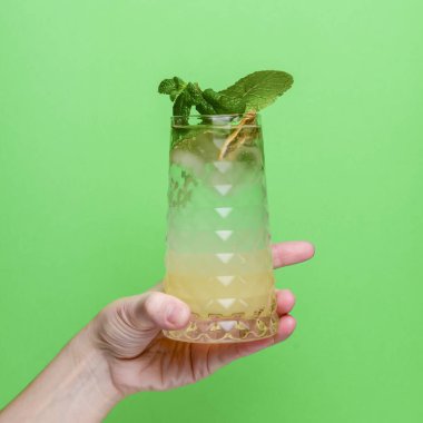 Parlak yeşil arka planda naneli limonata. Alkol içeceği, partide içmek için eğlenceli bir kokteyl. Yeşilde izole edilmiş.