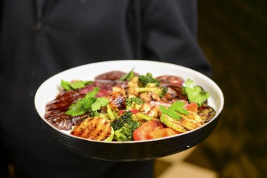 Kızarmış sebzeli ızgara biftek bifteği. Lokantada ya da lokantada garsonun verdiği lezzetli yemek, dışarıda yemek konsepti..