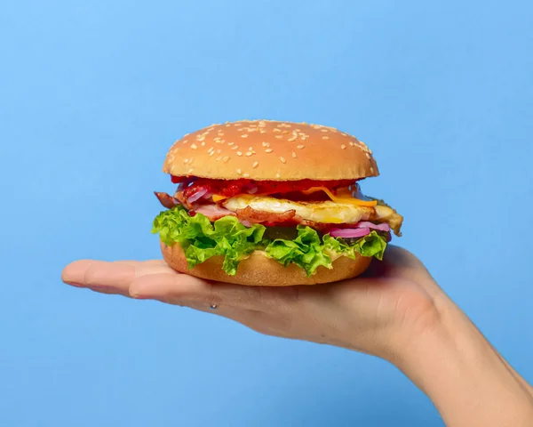 Ev yapımı sığır eti ızgara hamburger ve parlak mavi bir arka plan. Uzay afişini kopyala. Abur cubur, fast food konsepti.