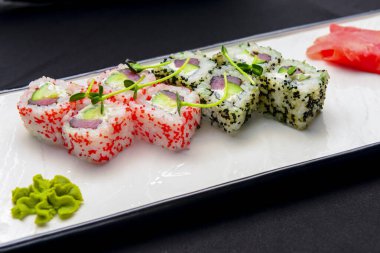 Ebiko siyah havyar, Japon usulü kırmızı havyar suşisi. Siyah arka planda beyaz tabakta servis edilmiş. Gelenek Japon mutfağı tarifi, Asya mutfağı konsepti.