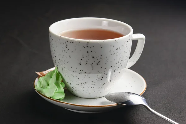 Cup of tea isolated on a black background. Black tea in a white cup, tea time. Close up.