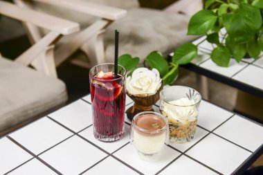 Üç tatlı vanilyalı çikolata ve bardakta kahve tatlısı ve bir meyve içeceği restoranda ya da kafede beyaz bir masada. Leaisure zamanı, dışarıda yeme konsepti..