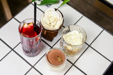 Üç tatlı vanilyalı çikolata ve bardakta kahve tatlısı ve bir meyve içeceği restoranda ya da kafede beyaz bir masada. Leaisure zamanı, dışarıda yeme konsepti..