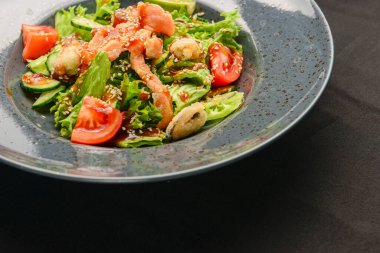 Siyah arka planda ton balığı ve sebze salatası. Sağlıklı yiyecekler, dışarıda yemek. Balık, domates, salatalık, taze marul..