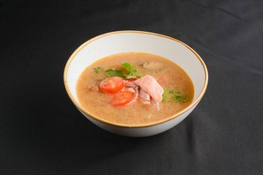 Siyah arka planda somon balıklı sebze çorbası. Yemek konsepti, sağlıklı sıcak çorba. Deniz yemekleri, Asya mutfağı konsepti..