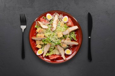 Siyah arka planda kırmızı Sezar Salatası. Geleneksel İtalyan mutfağı konsepti, geleneksel tarif. Kapat..