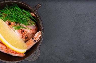 Limonlu karides ve siyah arka planda küçük siyah bir kase içinde taze dereotu. Deniz yemeği, sağlıklı mutfak konsepti. Kapat..