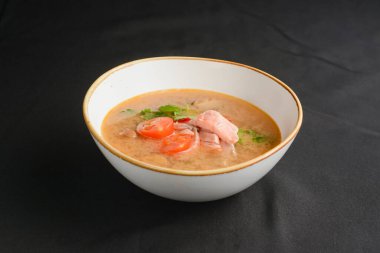 Siyah arka planda somon balıklı sebze çorbası. Yemek konsepti, sağlıklı sıcak çorba. Deniz yemekleri, Asya mutfağı konsepti..