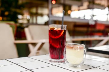 Bir tatlı vanilyalı çikolata ve bardakta kahve tatlısı ve bir meyve suyu restoranda veya kafede beyaz bir masada..