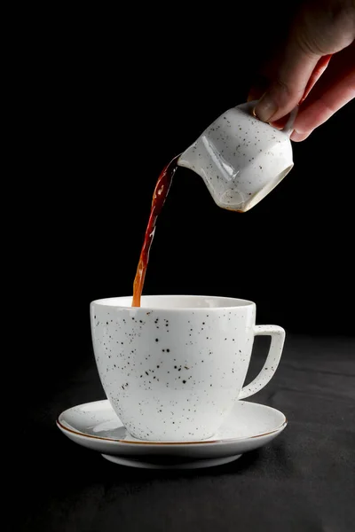 Teát töltök egy teáscsészének. Fekete háttérrel. Teaidő, fekete alapon izolálva. — Stock Fotó
