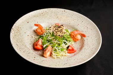 Domatesli pirinç eriştesi, taze marul salatası ve susam tohumları. Siyah arka planda Asya erişteli salata. Asya mutfağı kavramı.