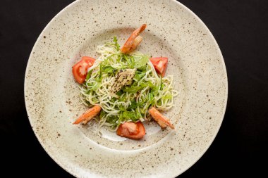 Domatesli pirinç eriştesi, taze marul salatası ve susam tohumları. Siyah arka planda Asya erişteli salata. Asya mutfağı kavramı.