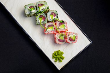 Havyarlı California maki suşisi. Yengeç eti, svokado, içinde salatalık. Siyah arka planda beyaz tabakta servis edilmiş. Japon mutfağı kavramı.