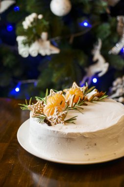 Kış Noel süslü Noel pastası, arka planda Noel ağacı. Üstünde mandalina olan çikolatalı vanilyalı pasta. 2021 Yeni Yıl Kutlaması.
