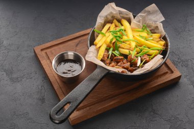 Kırsal ahşap tahta ve siyah arka planda demir bir tavada kızarmış patates. Rustik tarzı yemek, Ukrayna mutfağı konsepti. Et soslu patates..