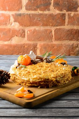 Mandalina ve noel kurabiyeleriyle süslenmiş geleneksel Napolyon pastası. Noel ya da yeni yıl pastası. Kırsal ahşap arka planda.