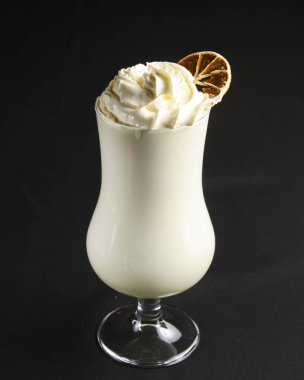 Kurutulmuş turunçgilli süt kokteyli. Siyah arka planda uzun bardakta vanilya kokteyli. Kapat..