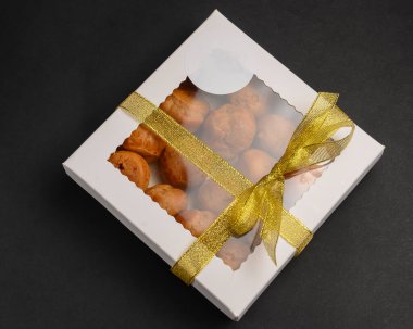 Siyah arka planda kurabiyelerle dolu karton kutu. Pasta teslimat kutusu, dünya çapında covid salgını nedeniyle paket servis konsepti..