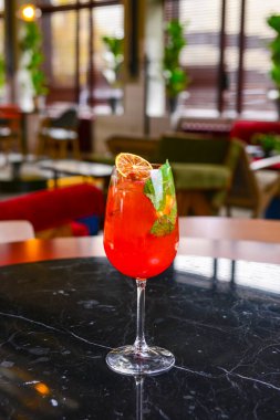 Meyve kokteyli içeceğini tazeliyorum. Siyah masanın üzerinde limon ve bulanık geri grond var. Restoranda ya da kafede, dışarıda yemek konsepti..
