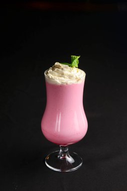 Siyah arka planda kokteyl bardağında çilekli smoothie. Lezzetli yaz soğuk kokteyli. Meyveler yakın..