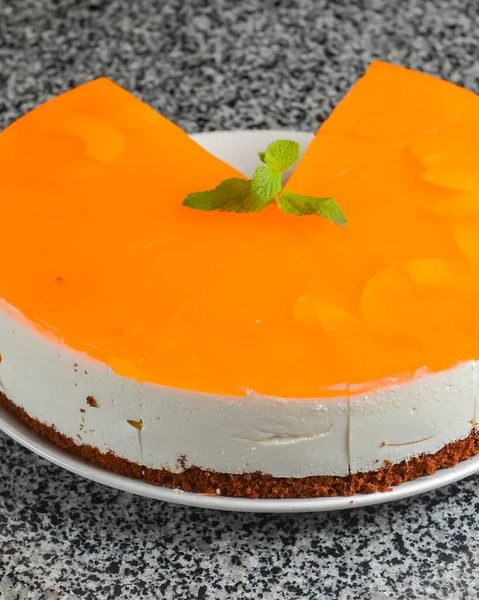 Mango cheesecake on white plate. Delicious sweet cake for tea or coffee time. Served over gray textured table.,