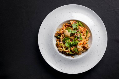 Deniz ürünleri tavası kızartması beyaz tabakta servis edilir. İstiridye ve karides tavası siyah üzerine izole edilmiş. Asya mutfağı kavramı.