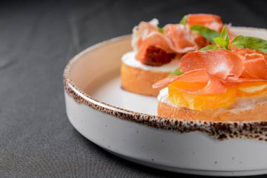 Sulu domates ve taze ekmek üzerine carpaccio eti ile taze meyve, üzerine sos. Geleneksel İtalyan mutfağı. Siyah arkaplan üzerinde beyaz plaka.