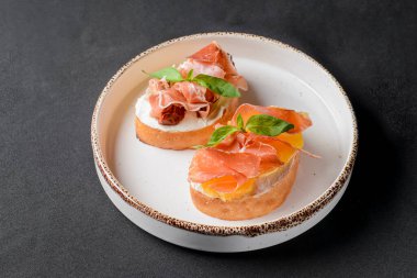 Sulu domates ve taze ekmek üzerine carpaccio eti ile taze meyve, üzerine sos. Geleneksel İtalyan mutfağı. Siyah arkaplan üzerinde beyaz plaka.