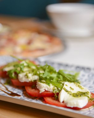 Klasik caprese salatası ve pizza. Arka planda bulanık bir fotoğraf. Geleneksel İtalyan mutfağı kavramı. Caprese salatasına odaklan..