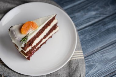 Vanilyalı çikolatalı kek. İçinde böğürtlen ve üstünde bir parça mandalina var. Gri ahşap kaplama arka planda beyaz bir tabakta servis edilmiş. Kahve ya da çay saati için tatlı..