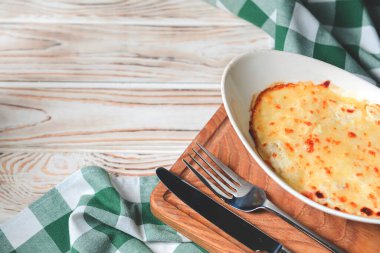 Köy ahşabının üzerinde beyaz bir tabakta servis edilen kıymalı bolonez soslu geleneksel lazanyaya yakın çekim..
