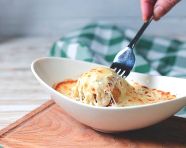 Köy ahşabının üzerinde beyaz bir tabakta servis edilen kıymalı bolonez soslu geleneksel lazanyaya yakın çekim..
