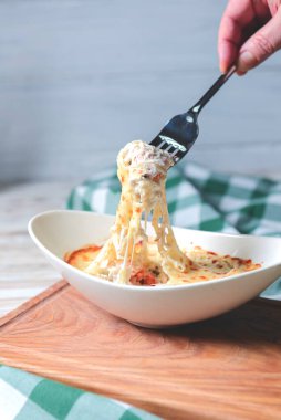 Köy ahşabının üzerinde beyaz bir tabakta servis edilen kıymalı bolonez soslu geleneksel lazanyaya yakın çekim..