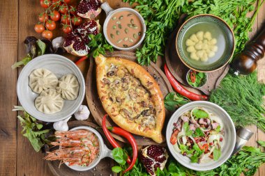Ahşap masada bir sürü yiyecek var. Gürcistan mutfağı. Üst manzara, düz yatış. Khinkali ve Gürcistan yemekleri