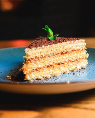 Kodlanmış süt, kakao ve yeşil naneli bal petekli waffle keki ahşap arka planda mavi bir tabakta servis edilir. Çay ya da kahve için lezzetli bir tatlı..