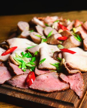 Beyaz tabak, roka üzerine Carpaccio sığır eti. Tahta bir tahtanın üzerinde farklı et parçaları. Bir restoranda hizmet ettim, dışarıda yemek yedim.,