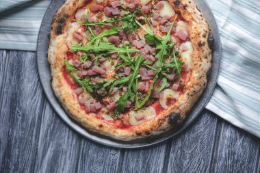 Somon balığı, peynir ve rustik gri ahşap arka planda taze roka ile pizza. İtalyan mutfağı konsepti, geleneksel pizza tarifi.