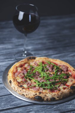 Somon balığı, peynir ve roka ile pizza ve kırsal gri ahşap arka planda bir bardak kırmızı şarap. İtalyan mutfağı konsepti, geleneksel pizza tarifi.