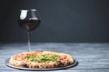 Somon balığı, peynir ve roka ile pizza ve kırsal gri ahşap arka planda bir bardak kırmızı şarap. İtalyan mutfağı konsepti, geleneksel pizza tarifi. Boşluk afişini kopyala.