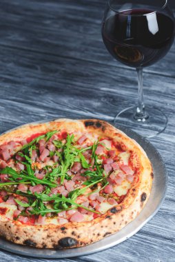 Somon balığı, peynir ve roka ile pizza ve kırsal gri ahşap arka planda bir bardak kırmızı şarap. İtalyan mutfağı konsepti, geleneksel pizza tarifi.