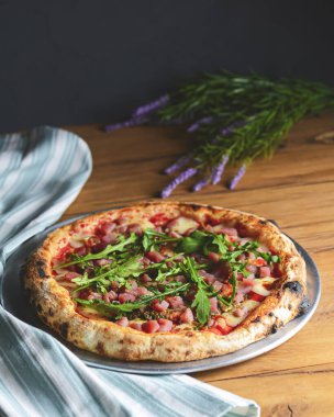 Kaba ahşap arka planda deniz ürünleri ve roka kaplı pizza. İtalyan mutfağı, İtalyan yemekleri..