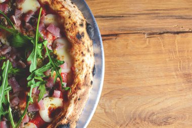 Kaba ahşap arka planda deniz ürünleri ve roka kaplı pizza. İtalyan mutfağı, İtalyan yemekleri..