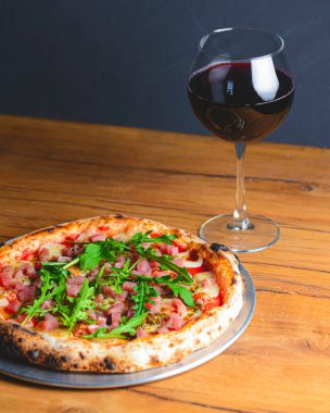 Somon balığı, peynir ve taze roka ile pizza ve bir bardak kırmızı şarap..