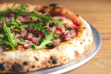 Kaba ahşap arka planda deniz ürünleri ve roka kaplı pizza. İtalyan mutfağı, İtalyan yemeği, geleneksel pizza tarifi..