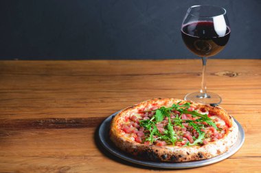 Somon balığı, peynir ve taze roka ile pizza ve kırsal gri ahşap arka planda bir bardak kırmızı şarap. İtalyan mutfağı konsepti, geleneksel pizza tarifi.