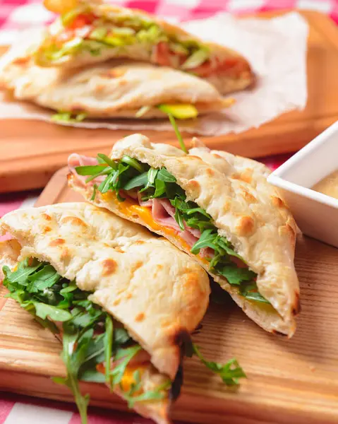 Jambon ve taze sebzeler. Tahta masada, üzerinde kırmızı ekose masa örtüsü olan pide ekmeği. Lezzetli kahvaltı konsepti, İtalyan mutfağı..